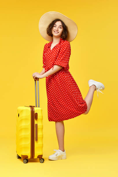 istock woman with suitcase going traveling on yellow background. 1310559620