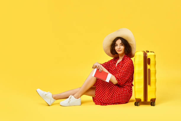 istock woman with suitcase going traveling on yellow background. 1310559665