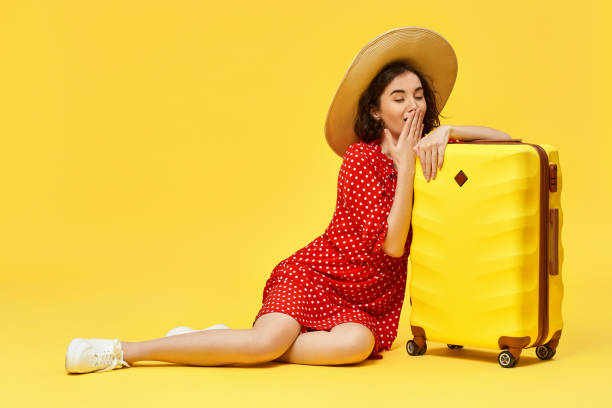 istock woman with suitcase going traveling on yellow background. 1310559676