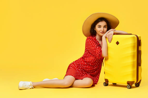 istock woman with suitcase going traveling on yellow background. 1310559684