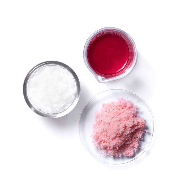 Close up inorganic chemical on white laboratory table (Top View). Pink flake chemicals in Chemical Watch Glass, Red EPOXY liquid rasin in beaker, Microcrystalline wax in glass container. cerca de productos químicos inorgánicos en la mesa de laboratorio blanca (vista superior). productos químicos de escamas rosas en vidrio de reloj químico, rasína líquida epoxy roja en vaso de precipitados, cera microcristalina en recipiente de vidrio