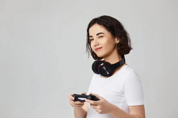 beautiful curly involved girl playing video games on the console on gray background