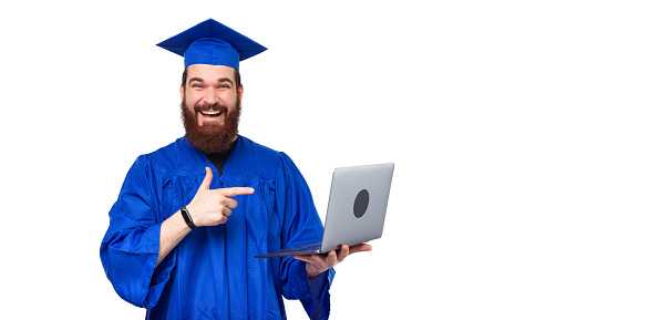 Happy smiling student man wearing blue bachelor pointing at laptop.