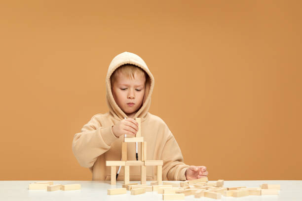 children plays with wooden constructor on desk.