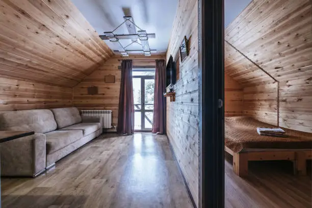 Simple wooden interior of hall and bedroom in mountain resort guesthouse