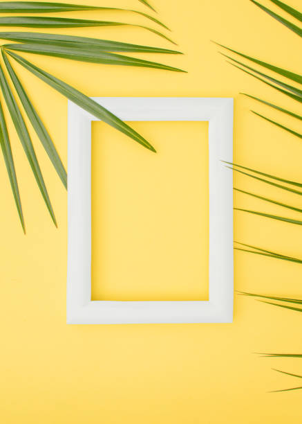 istock Frame and palm leaves on a yellow vertical background. Tropical summer white frame concept on Illuminating background. 1310574770