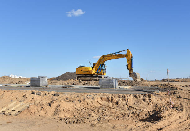 istock Excavator on earthmoving at construction site. Backhoe digs sand on blue sky background 1310578825