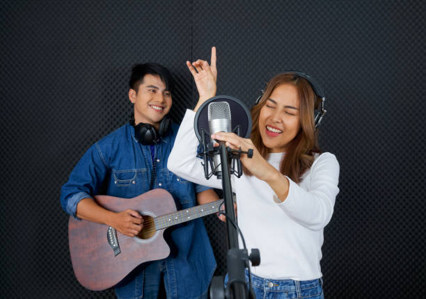 junge asiatische frau tanzen, schwanken und heben ihre arme rhythmisch beim singen. musiker, die musik im professionellen tonstudio produzieren. - chorus girl stock-fotos und bilder