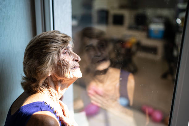 istock Senior woman looking through the window at home 1310584543