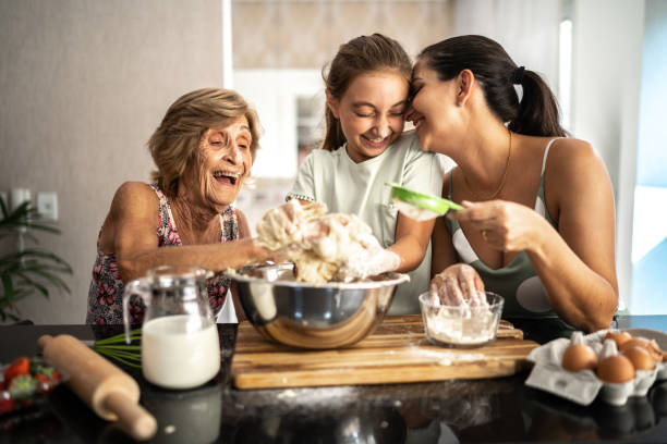mehrgenerationenfamilie bereitet brot/kuchen zu hause zu - grandmother cooking baking family stock-fotos und bilder
