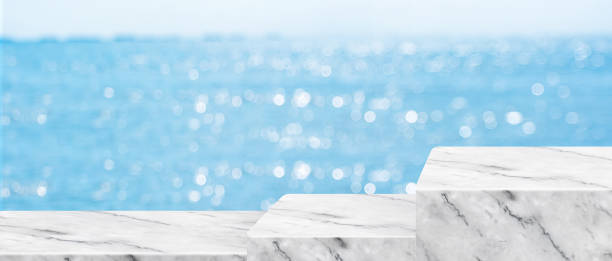 istock Empty white pedestal step marble table with blur sea bokeh banner background Mockup template for product display advertise on online media 1310587292