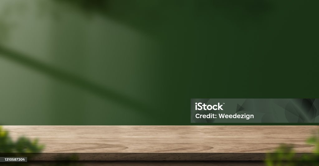 wood table green wall background with sunlight window create leaf shadow on wall with blur indoor green plant foreground.panoramic banner mockup for display of product.eco friendly interior concept Table Stock Photo