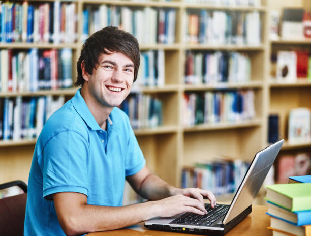 istock Happy male student working at his laptop computer in a university library 1310589478