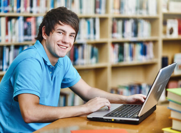 istock Happy male student working at his laptop computer in a university library 1310589696