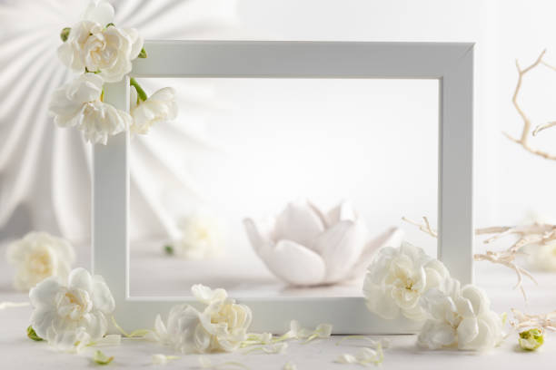 istock Still life with white flowers and frame on light backdrop. 1310590565