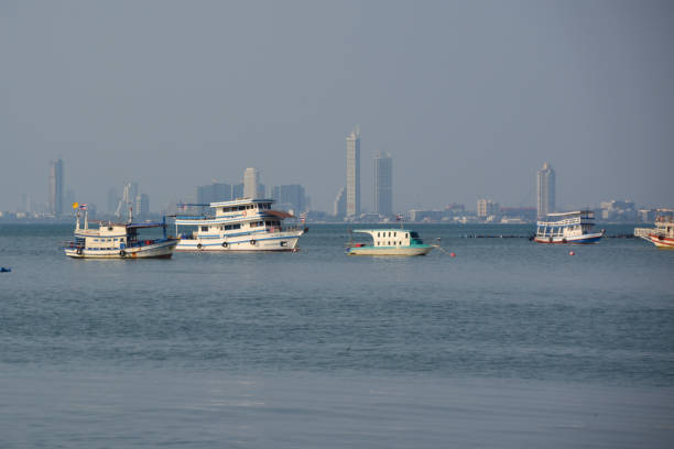 View of moored boats with Jomtien skyline in the distance, Pattaya, Thailand.