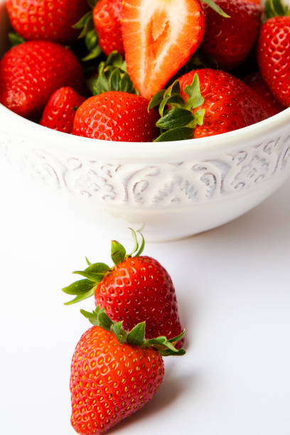 istock Red strawberries in a white bowl, plain background 1310594342