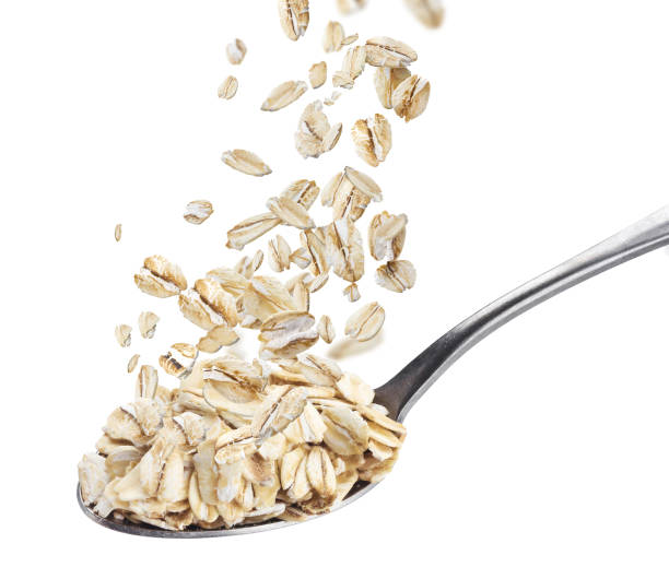 istock Oat flakes falling on spoon isolated on white background 1310594690