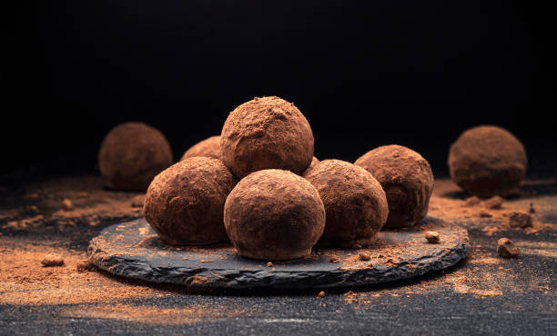Chocolate truffles, round chocolate candies on black background Chocolate truffles, round chocolate candies on black slate background with cocoa powder chocolate truffle stock pictures, royalty-free photos & images