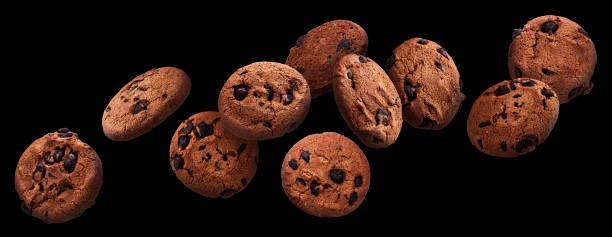 biscuits de puce de chocolat tombant au-dessus du fond noir - chocolate chip cookie cookie preparing food chocolate photos et images de collection