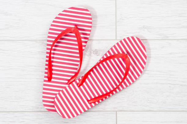 Red flip flops on a white wooden background close up