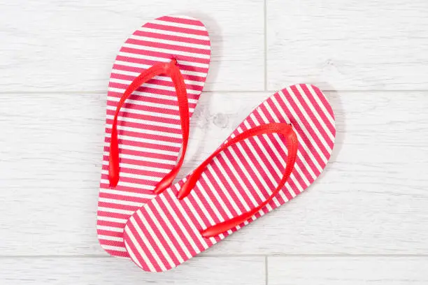 Red flip flops on a white wooden background close up