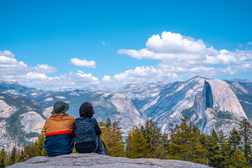 A couple sitting in Sentinel Dome looking at Yosemite National Park. United States\