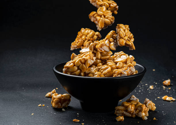 istock Peanut kozinaki falling in bowl on black background 1310604659