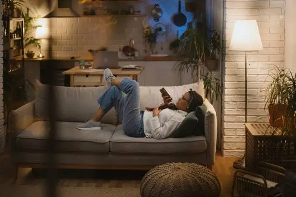 Photo of Woman using voice assistant on smart phone in her home late at night