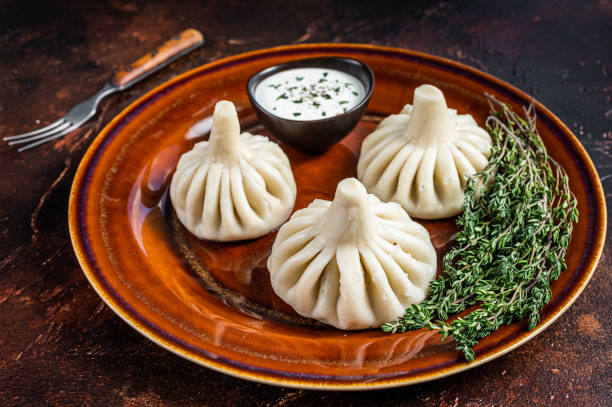 istock Khinkali Dumplings with beef and lamb meat on rustic plate with herbs. Dark background. Top view 1310610764