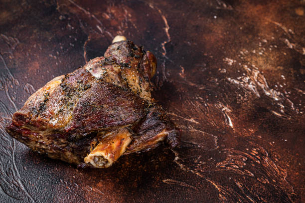 istock Roast Lamb leg with herbs and garlic. Dark background. Top view. Copy space 1310612901