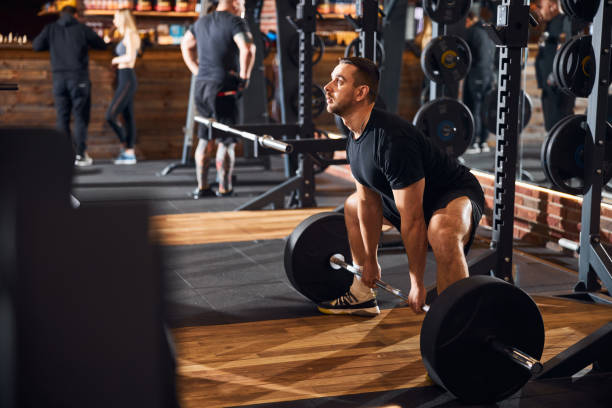 istock Serious sportsman is leaning forward while weight-lifting 1310613594