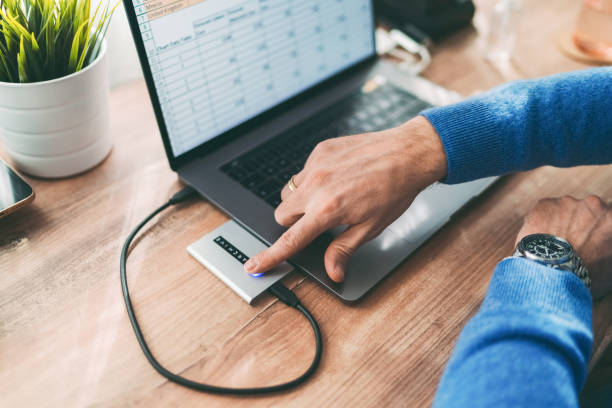 Working at home Close-up photo of man at work unlocking external hard disk drive with fingerprint authentication external hard disk drive stock pictures, royalty-free photos & images