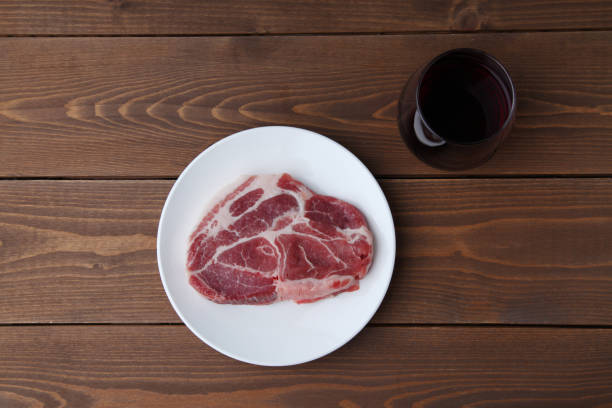 carne de cerdo cruda y vaso de vino tinto aislado en mesa de madera - fillet meat portion fillet steak fotografías e imágenes de stock