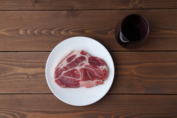 carne de porco crua e taça de vinho tinto isolado em mesa de madeira - fillet meat portion fillet steak - fotografias e filmes do acervo