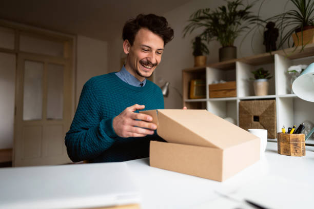 istock Cheerful young man opening delivery package at home 1310616678
