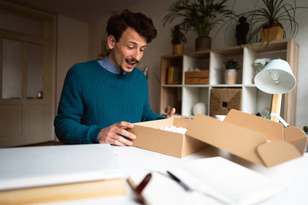 istock Happy man opening delivery package at home 1310616695