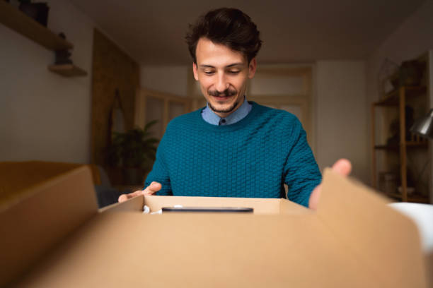 istock Cheerful male customer opening delivery package at home 1310616731