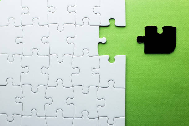 istock white puzzle with one piece missing to complete, but the missing piece is black and not the right shape. green background with copy space 1310618235