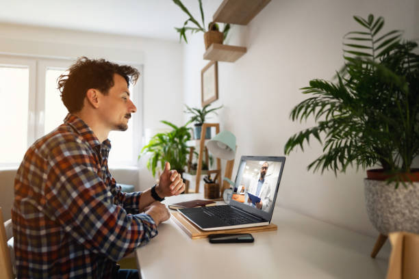 istock Man video conferencing with his doctor on a laptop at home 1310620367