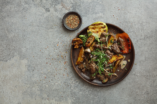 Brazilian Skirt Steak with grilled vegetables. Flat lay top-down composition on concrete background.