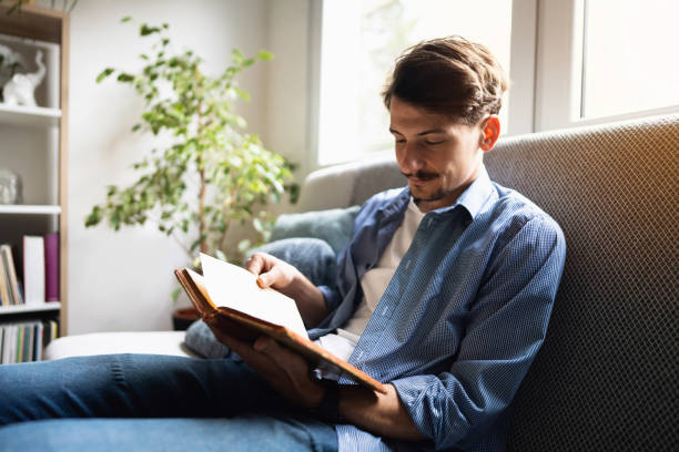 istock Handsome Caucasian man reading a book at home 1310623168
