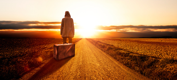 Young woman with a suitcase at sunset