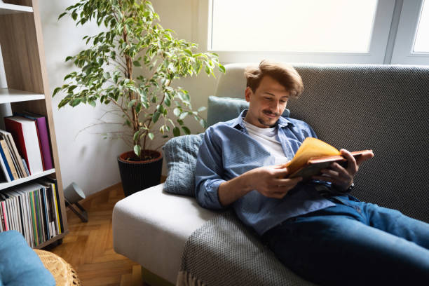istock One young man lying on the sofa and reading a book 1310623197
