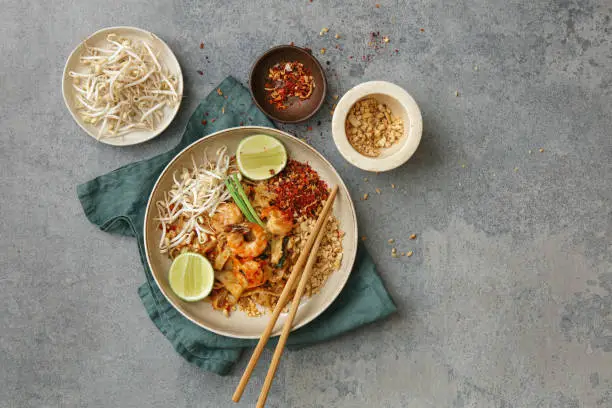 Authentic classic Pad Thai with shrimps. Flat lay top-down composition on concrete background.