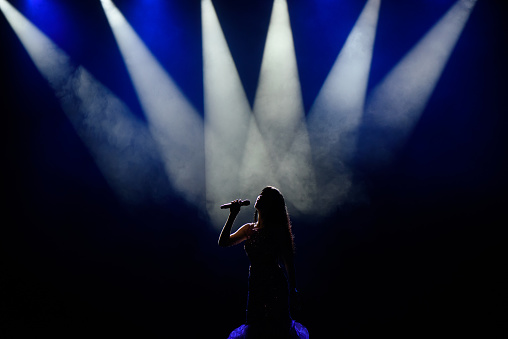 A young woman singer in silhouette on stage during a concert