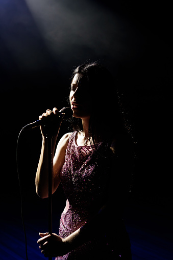 Portrait of beautiful singing woman on dark background