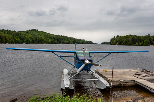 small seaplane moored to a floating pontoon near the shore of a mountain lake. Adirondacks, NY