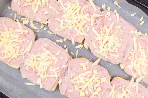 Photo of Baked Sandwiches with ham and cheese on the baking tray