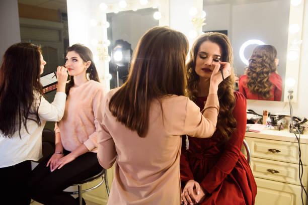 istock Make-up artist applying bright base color eyeshadow on model's eye and holding a shell with eyeshadow on background, close up. 1310637968